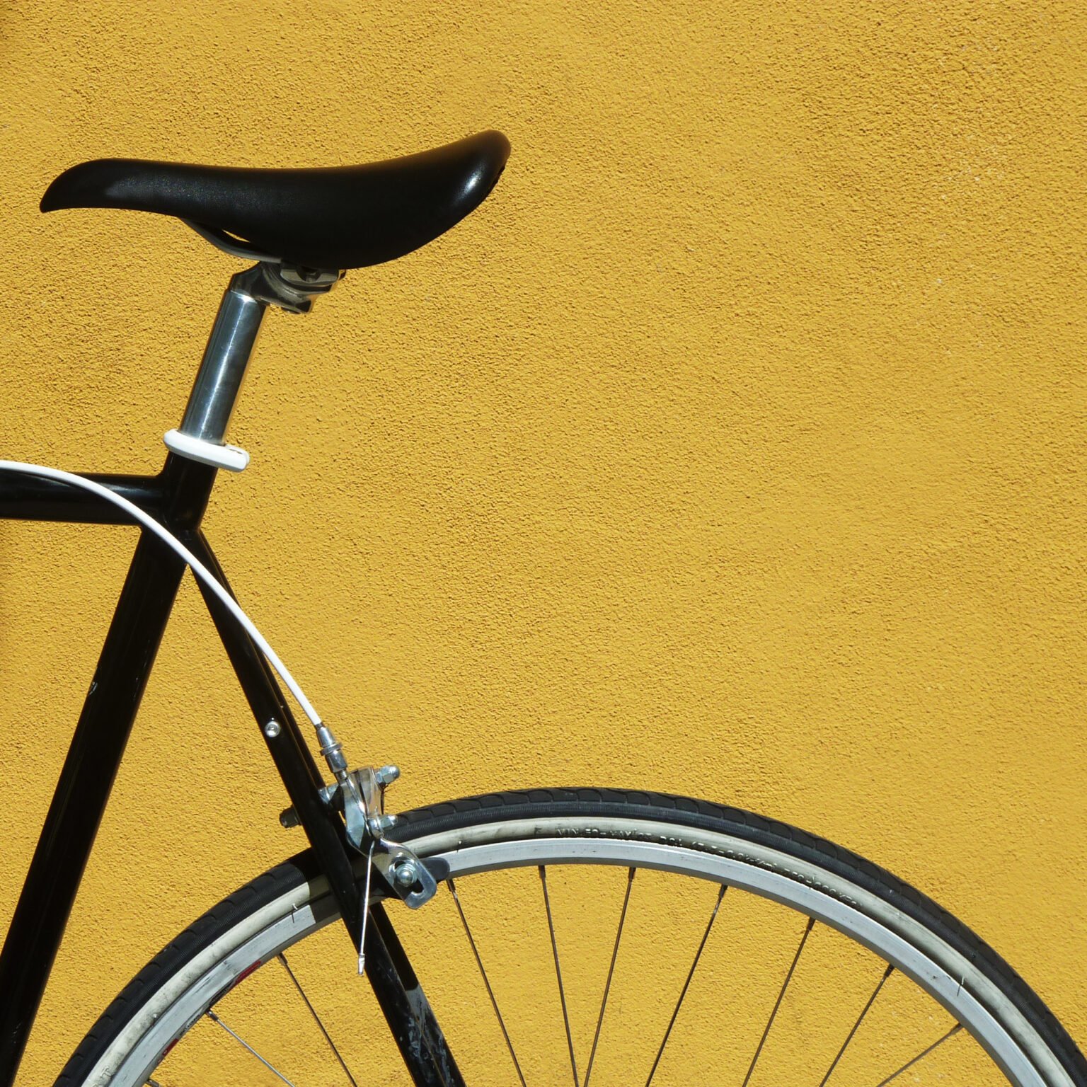 Black bike against a yellow wall Detail of a black bicycle against a yellow wall