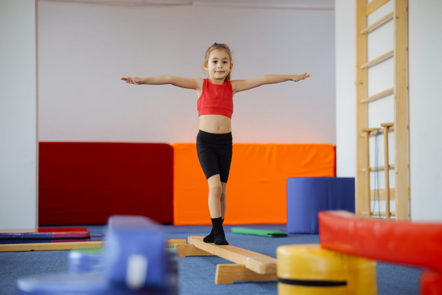 Happy girl during corrective gymnastics Cute active child girl in sensory integration room, kindergarten. Kid is active leisure. Childhood and sporty lifestyle.Sports weekend in gymnastic center. Fitness,healthy, develop skills concept