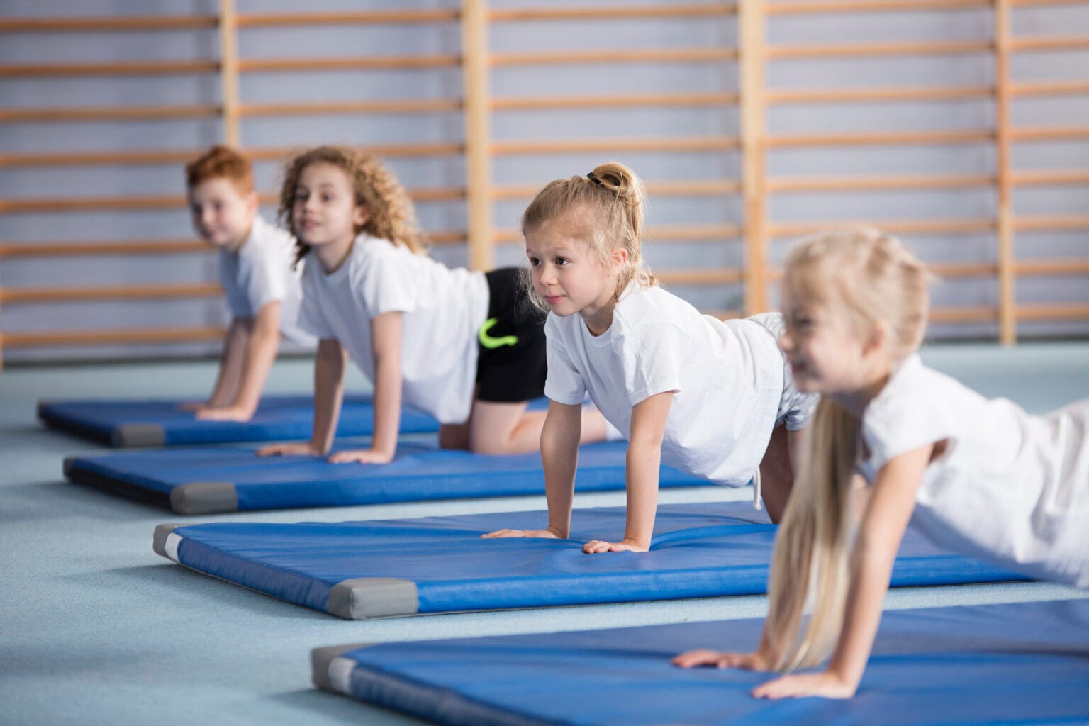 Happy girl during corrective gymnastics Happy girl exercising on blue mat during corrective gymnastics classes