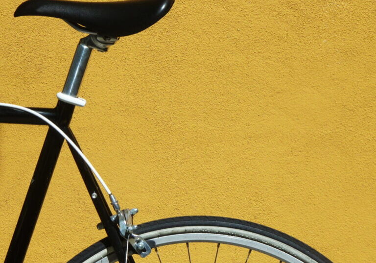 Black bike against a yellow wall Detail of a black bicycle against a yellow wall